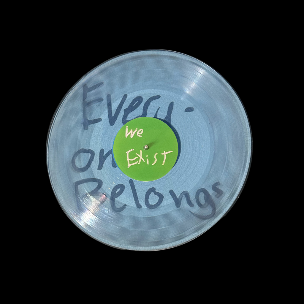 A photograph of Side A of the On the Record vinyl. Words on the vinyl read "Everyone belongs. We exist."